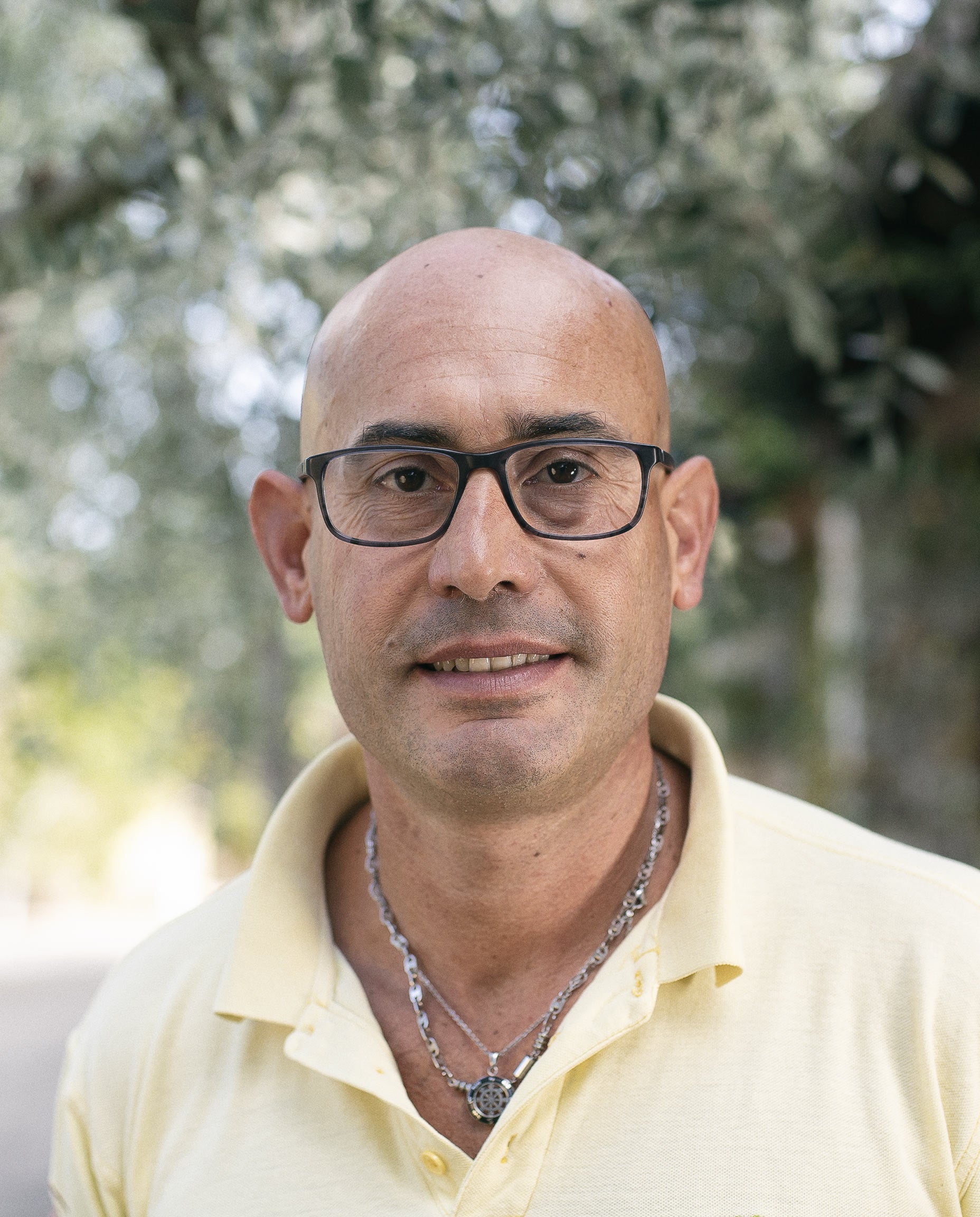 Vincenzo Vieste con gli occhiali tra gli ulivi: segue la produzione in frantoio. Oleificio Fratelli Vieste