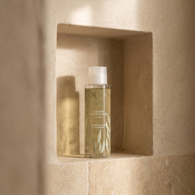 Lozione tonificante viso Olea Cosmetic, gesto d'uso in ambiente bagno. Oleificio Fratelli Vieste