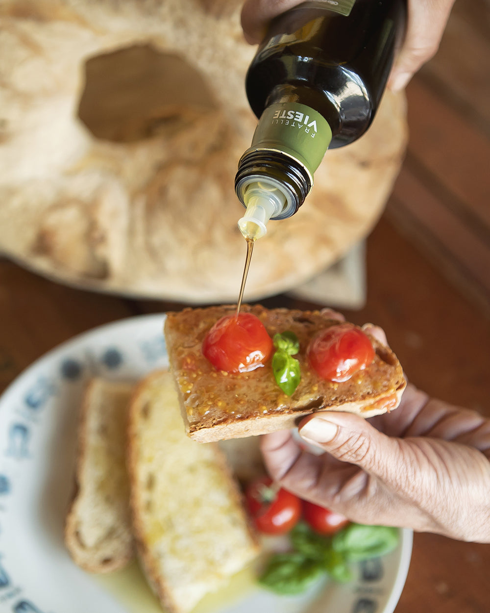 Olio extravergine Vieste versato su una bruschetta con pomodorini e basilico. Oleificio Fratelli Vieste